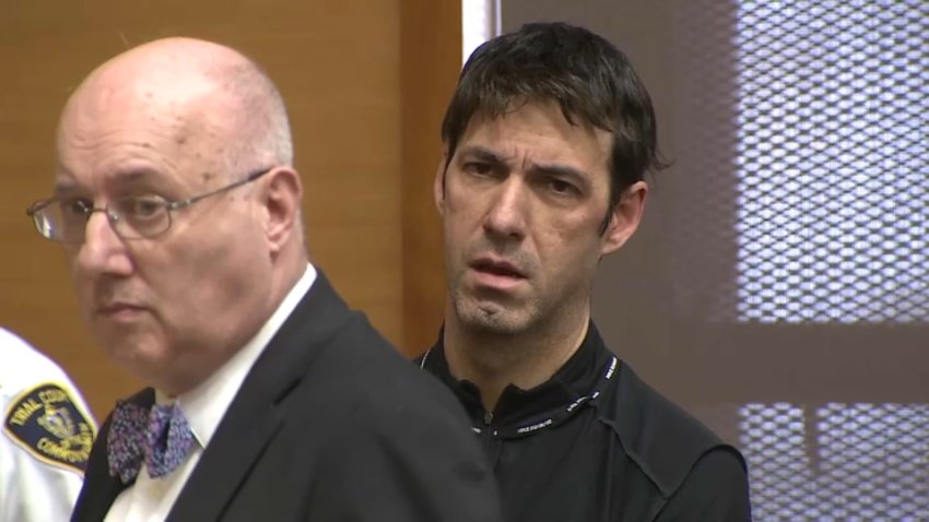 Michael Chicolella standing behind his court-appointed lawyer in Framingham District Court to face charges involving images of child sex abuse on Friday, March 7, 2025.